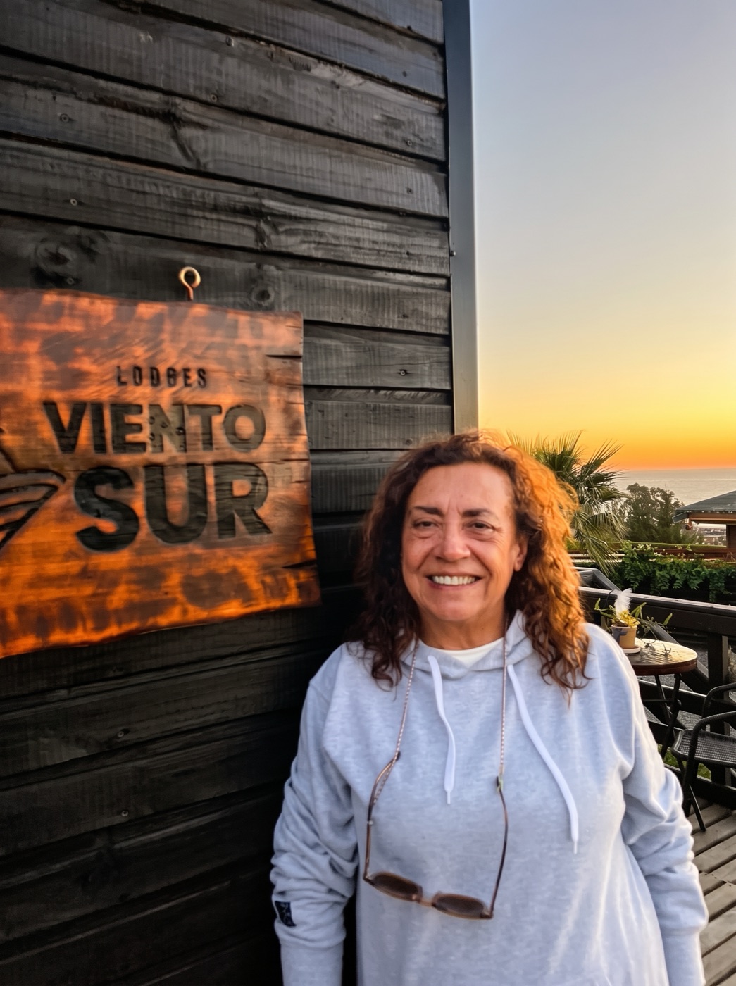 Alejandra, fundadora de Viento Sur, junto al letrero del lodge al atardecer
