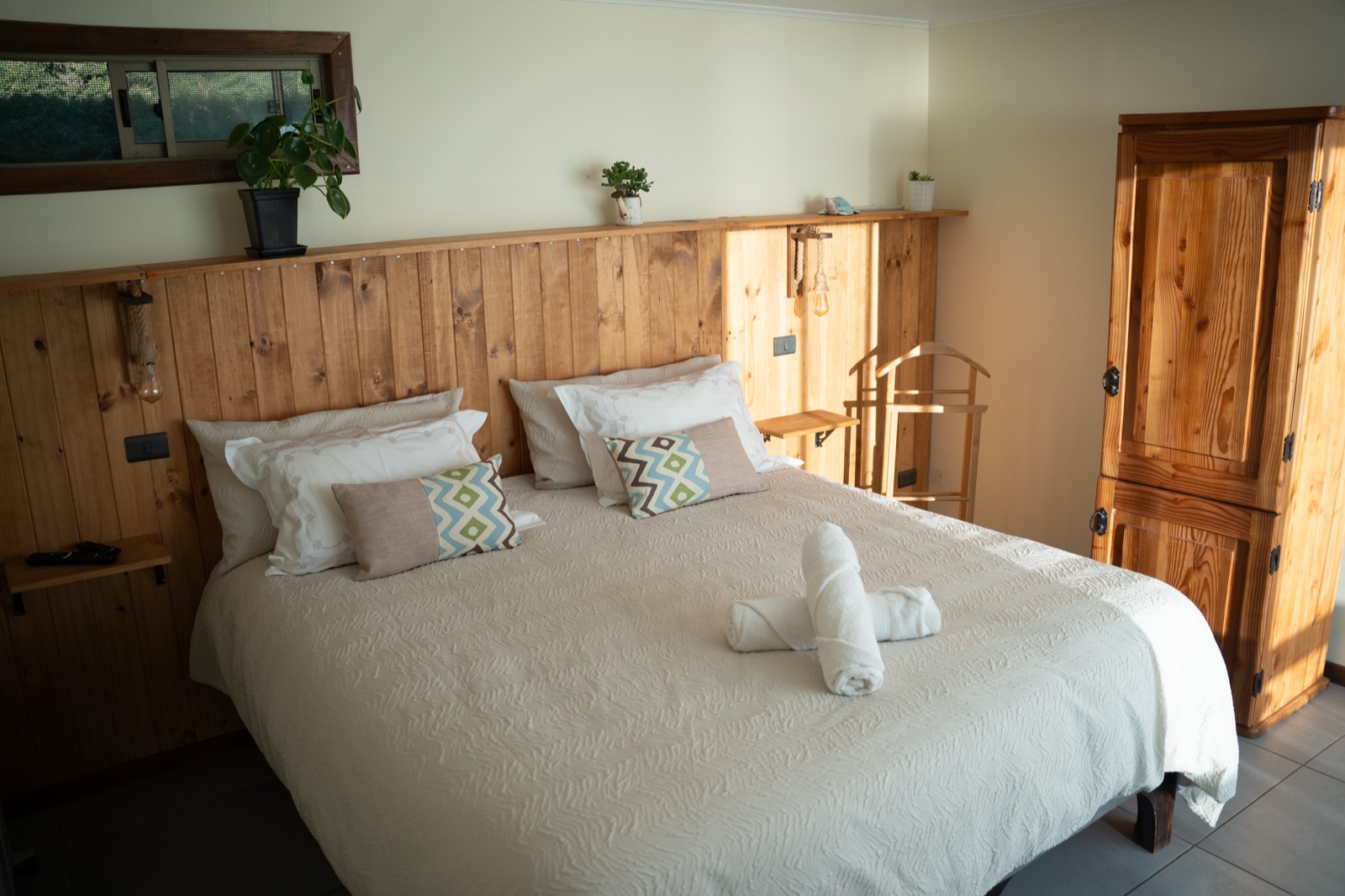 Cama king de la suite con velador y closet de madera